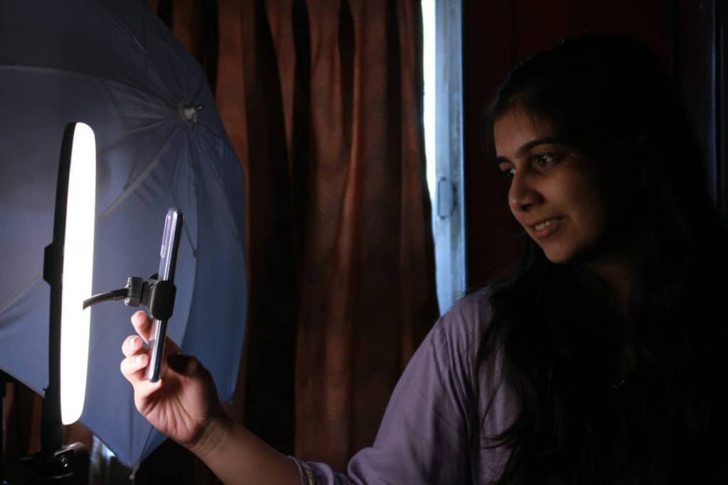 femme tenant un téléphone portable devant une lumière