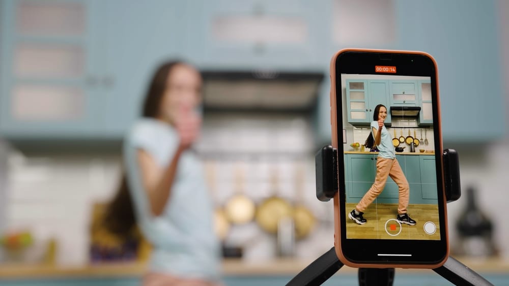 Jeune femme dans une cuisine qui se filme avec un smartphone au premier plan